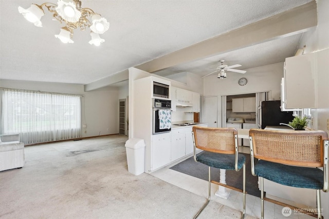 kitchen with stainless steel microwave, wall oven, vaulted ceiling, white cabinets, and gas cooktop