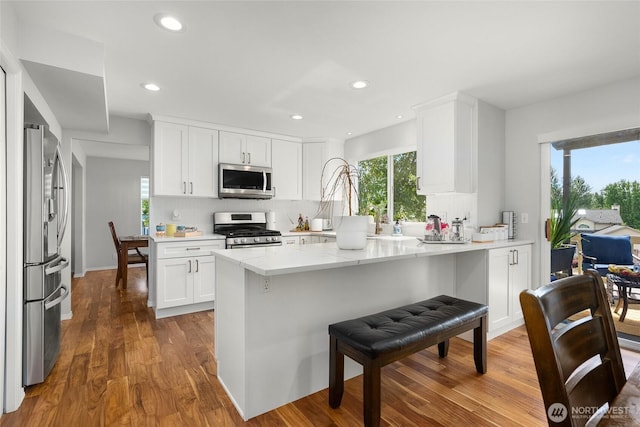 19013 112th Pl SE, Renton, WA 98055 - kitchen with appliances with stainless steel finishes, dark wood-type flooring, a kitchen bar, white cabinetry, and recessed lighting