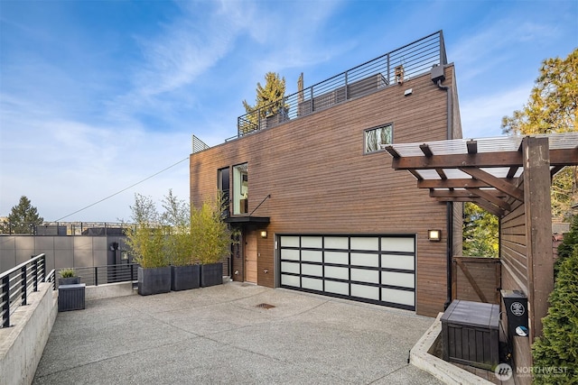 view of side of home featuring a garage, fence, driveway, and a pergola