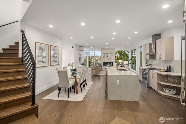 kitchen featuring modern cabinets, a sink, dark wood-style floors, wall chimney exhaust hood, and stainless steel gas range