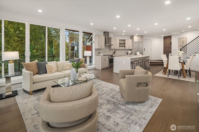 living room featuring dark wood finished floors, a wall of windows, stairway, and recessed lighting