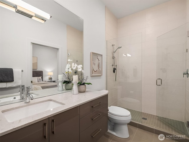 ensuite bathroom with toilet, a stall shower, ensuite bathroom, tile patterned floors, and vanity