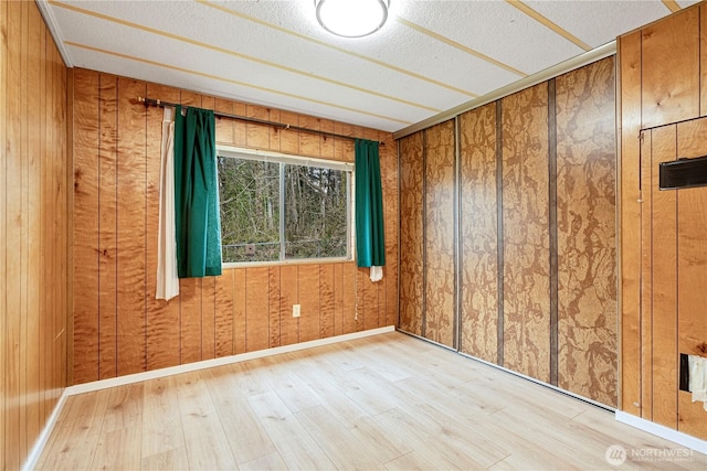 unfurnished room with a textured ceiling, baseboards, and wood finished floors