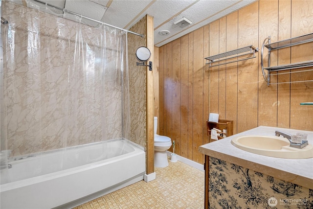 bathroom featuring a sink, wooden walls, toilet, and shower / tub combo