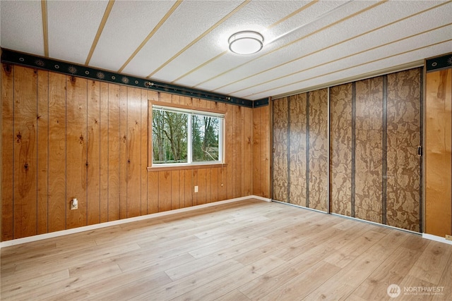 empty room with a textured ceiling, baseboards, and wood finished floors