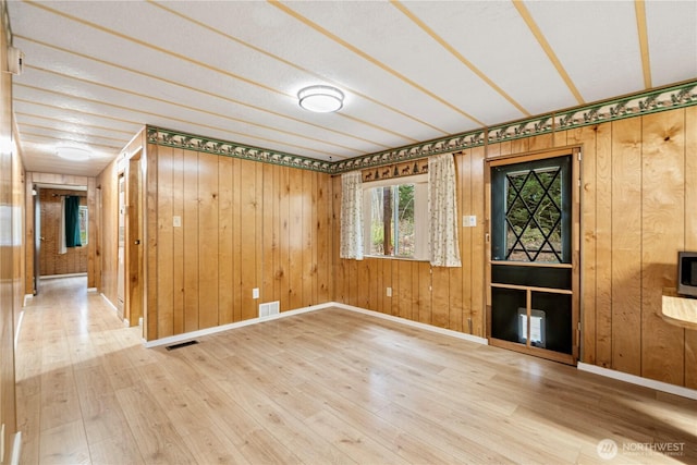 unfurnished room featuring visible vents, baseboards, and wood finished floors