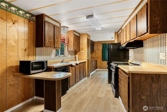 kitchen featuring a peninsula, a sink, stainless steel appliances, under cabinet range hood, and light wood-type flooring