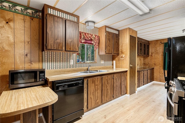 kitchen with black appliances, light countertops, light wood-style floors, and a sink