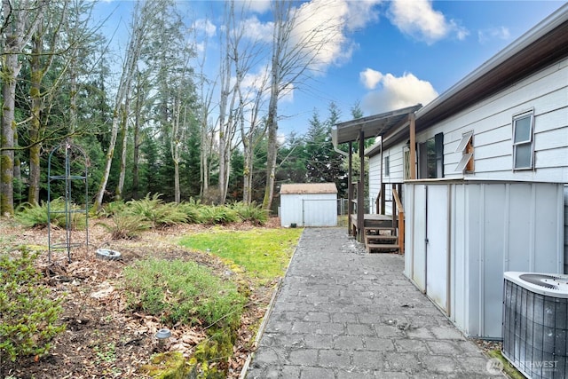 view of yard featuring an outbuilding, cooling unit, and a storage unit