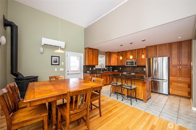 dining area with recessed lighting, light wood-style flooring, a wall mounted AC, and a wood stove