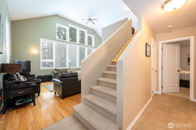 stairs with tile patterned floors, baseboards, ceiling fan, and vaulted ceiling