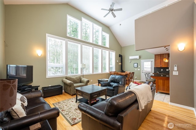 living room featuring light wood-style flooring, baseboards, high vaulted ceiling, and ceiling fan