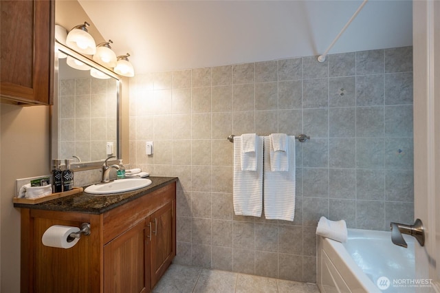 bathroom with tile patterned flooring, a bathtub, tile walls, and vanity