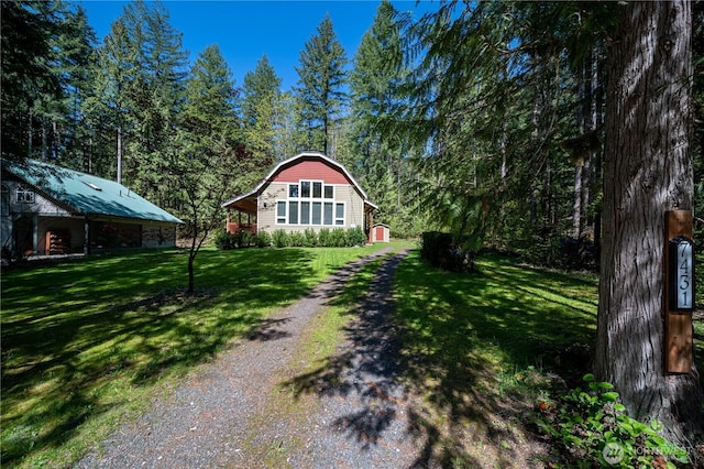 view of yard with an outbuilding and a view of trees