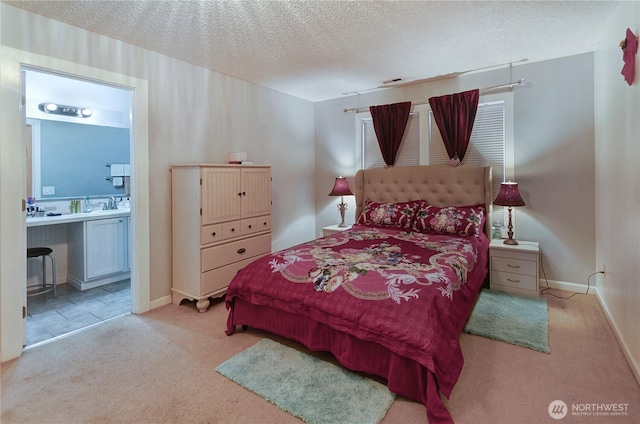 bedroom featuring visible vents, carpet, a textured ceiling, ensuite bath, and a sink