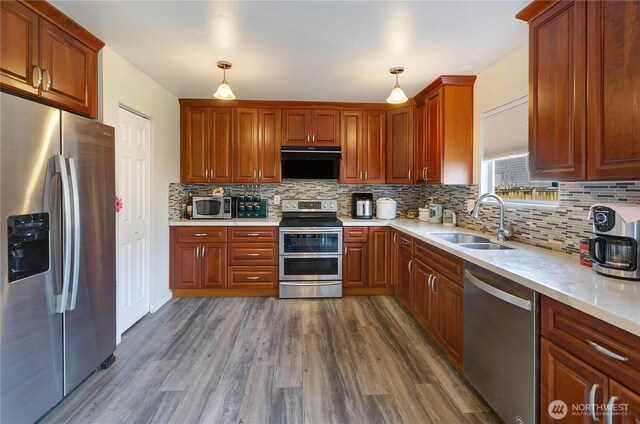 kitchen featuring dark wood-type flooring, a sink, stainless steel appliances, light countertops, and extractor fan