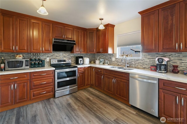 kitchen with ventilation hood, light countertops, dark wood-style floors, stainless steel appliances, and a sink