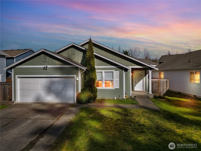 view of front facade featuring a lawn, driveway, fence, board and batten siding, and an attached garage