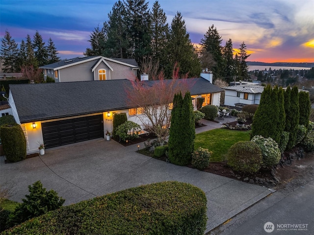 view of front of home featuring an attached garage, driveway, and a shingled roof