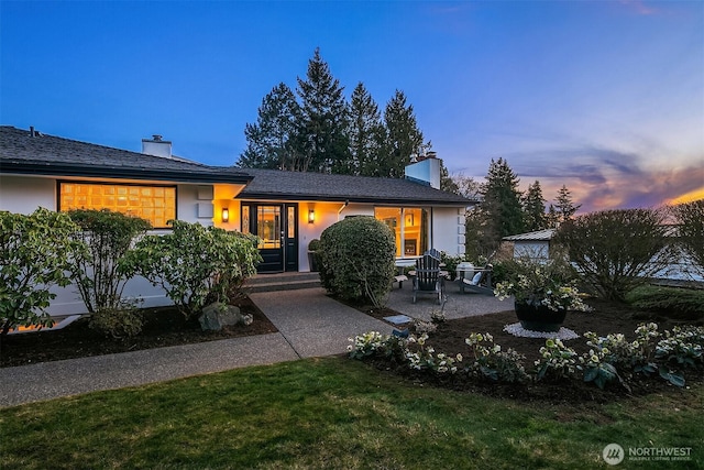 view of front of property with stucco siding, a patio area, and a chimney