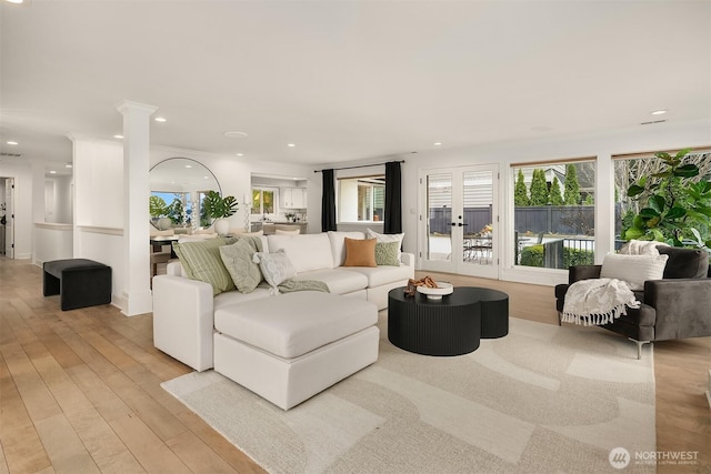 living room featuring recessed lighting, light wood-style floors, and decorative columns