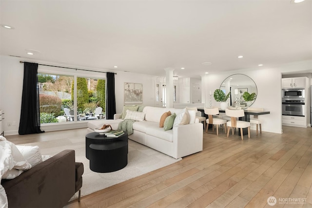 living area featuring recessed lighting, light wood-style flooring, and ornate columns