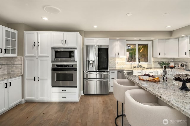 kitchen featuring decorative backsplash, hardwood / wood-style flooring, appliances with stainless steel finishes, and white cabinetry