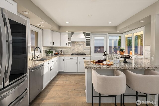 kitchen with premium range hood, a kitchen bar, a sink, backsplash, and stainless steel appliances