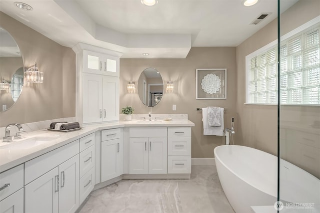 full bath with visible vents, double vanity, a soaking tub, marble finish floor, and a sink