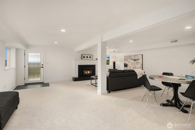 living room featuring recessed lighting, light colored carpet, baseboards, and a lit fireplace