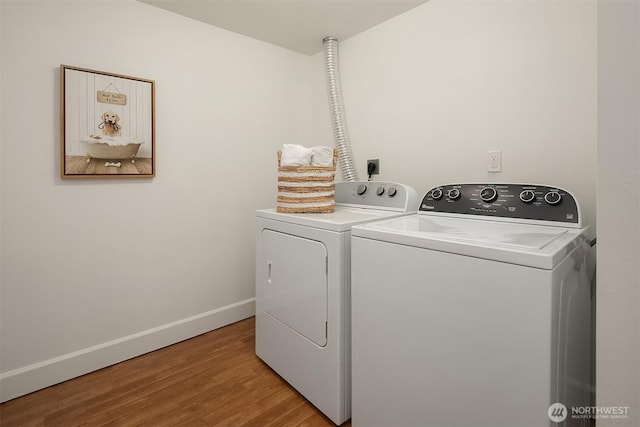 clothes washing area featuring laundry area, independent washer and dryer, light wood-style flooring, and baseboards