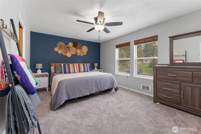 bedroom featuring ceiling fan, light colored carpet, visible vents, and baseboards