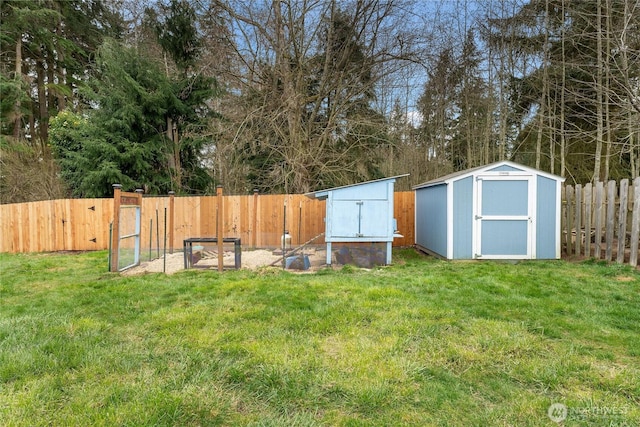 view of yard featuring an outbuilding, a fenced backyard, and a shed