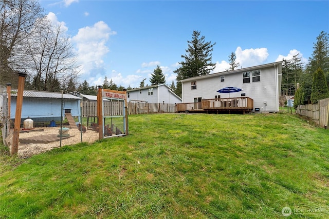 view of yard with a deck, an outbuilding, a fenced backyard, and exterior structure