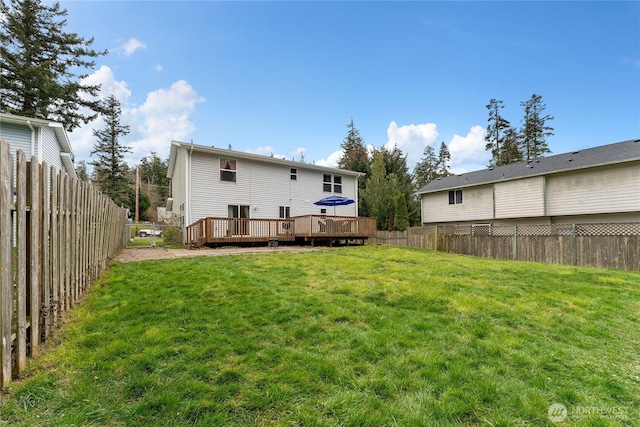 back of property with a fenced backyard, a yard, and a deck