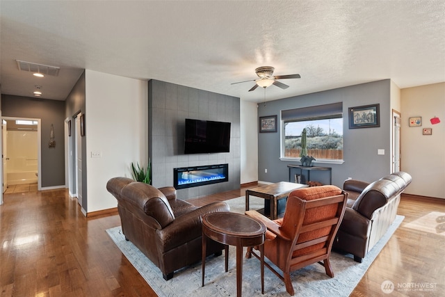 living room with visible vents, baseboards, a ceiling fan, and wood finished floors