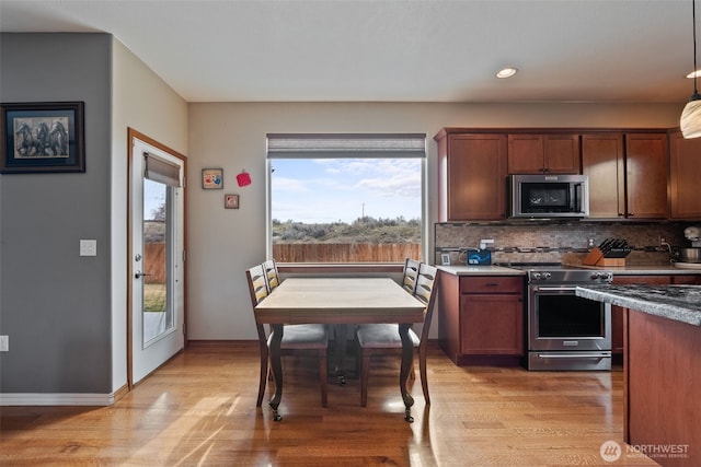 kitchen with backsplash, baseboards, light wood-type flooring, and appliances with stainless steel finishes