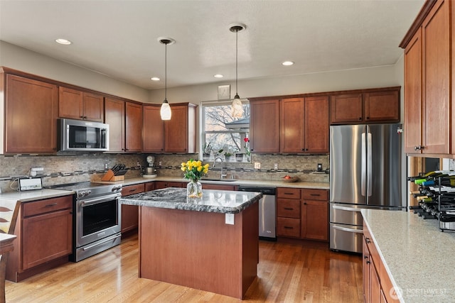 kitchen with a sink, decorative backsplash, appliances with stainless steel finishes, light wood-type flooring, and a center island