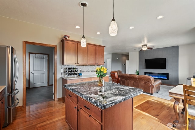 kitchen featuring wood finished floors, open floor plan, freestanding refrigerator, decorative backsplash, and ceiling fan