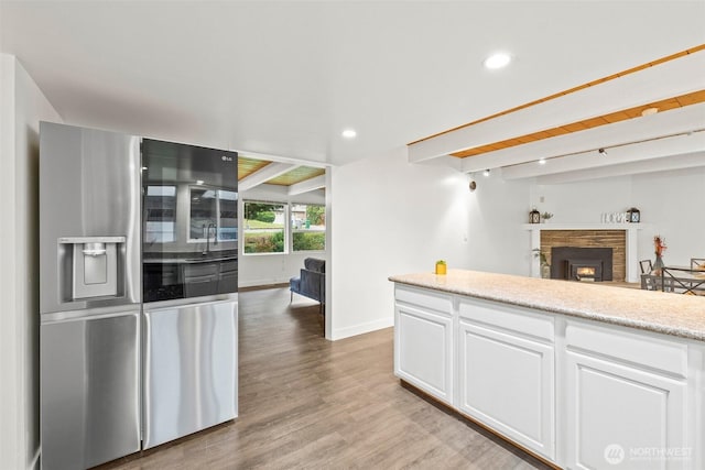 kitchen featuring beam ceiling, white cabinetry, recessed lighting, stainless steel fridge, and light wood finished floors