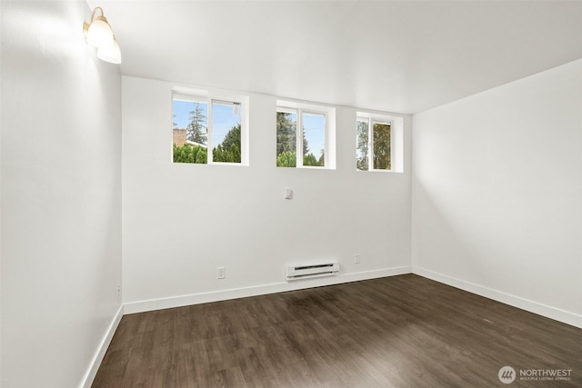 empty room featuring dark wood-style flooring, baseboards, and a baseboard radiator