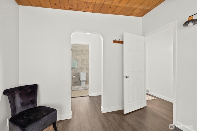 living area featuring dark wood-style floors, wooden ceiling, baseboards, and arched walkways