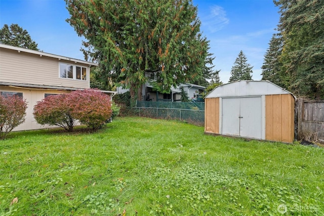 view of yard featuring a storage unit, an outbuilding, and fence