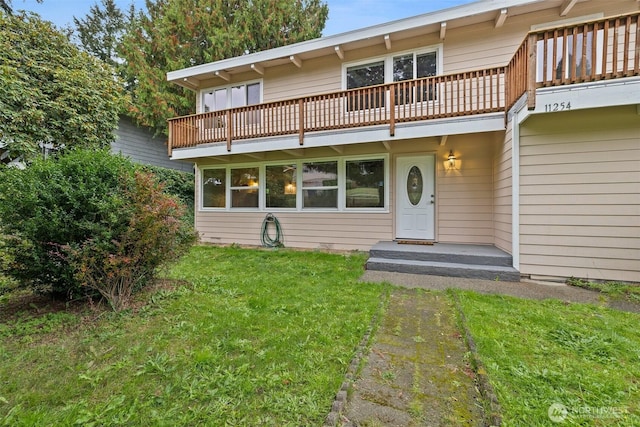 rear view of house featuring a yard and a balcony