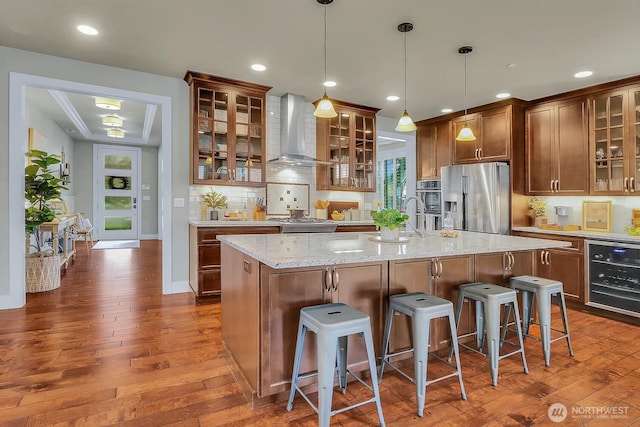 kitchen featuring dark wood-type flooring, wall chimney range hood, wine cooler, and appliances with stainless steel finishes