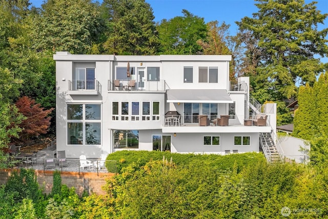 back of house with stairway, stucco siding, and a balcony