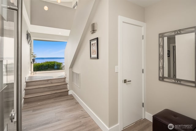 hall with visible vents, baseboards, and wood finished floors