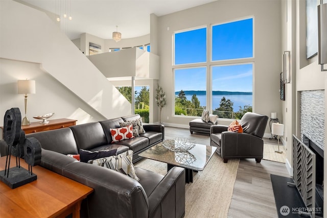 living room with a water view, wood finished floors, baseboards, and a towering ceiling