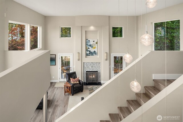 staircase featuring wood finished floors, a towering ceiling, and a tile fireplace