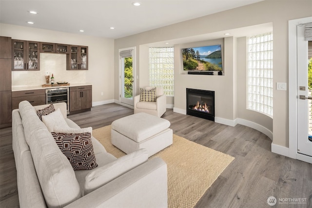 living room featuring beverage cooler, recessed lighting, a bar, and wood finished floors